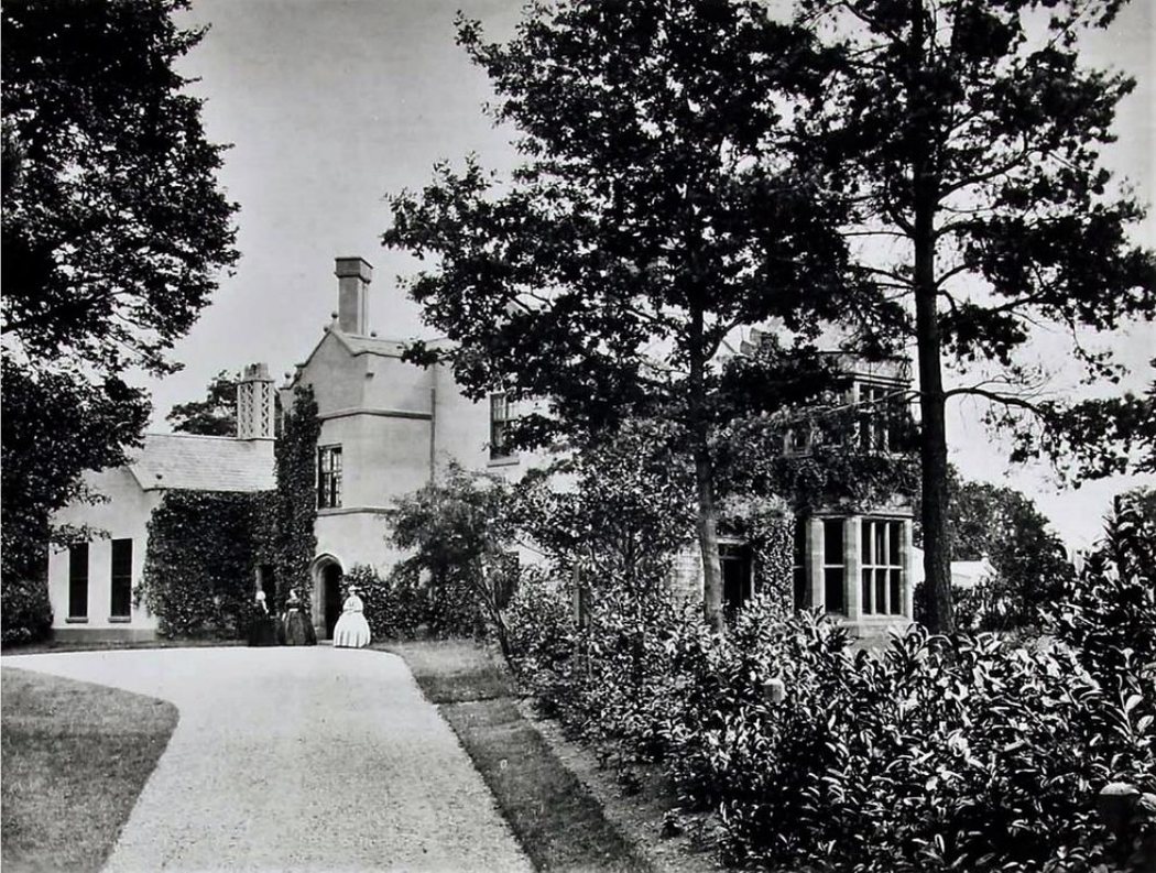 Photograph of Chorlton Hall circa 1855, the earliest known photograph of the house, showing the entrance front with a single-storey east extension and two figures on the drive