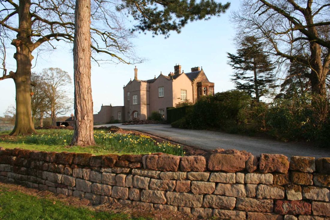 The parkland wall and mature trees at Chorlton Hall in spring